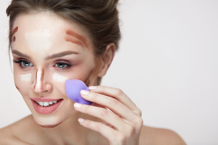 Žena testujúca rôzne druhy make-upu na tvári.